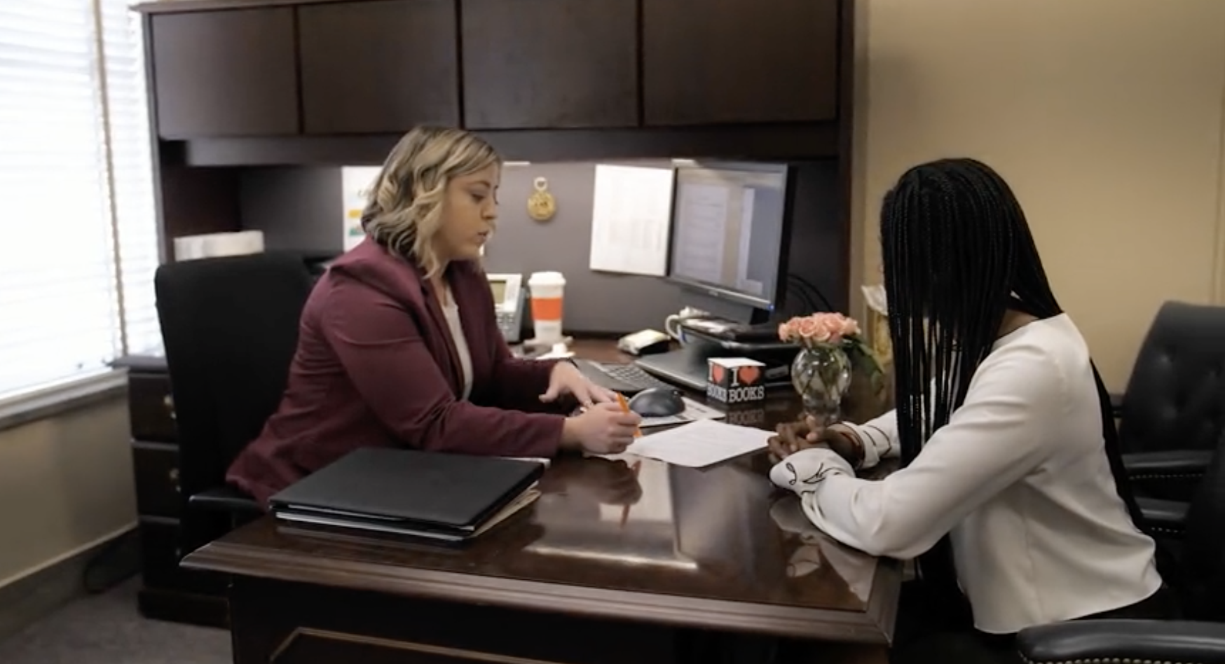 Two women sitting at a desk looking at a document